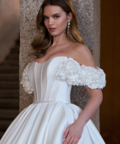 Elegant mikado-top med rundad urringning, 3D-blommor och korsad detalj i ryggen. Perfekt för bruden som vill ha en romantisk och sofistikerad brudlook. Finns även i satin – Novel-B.