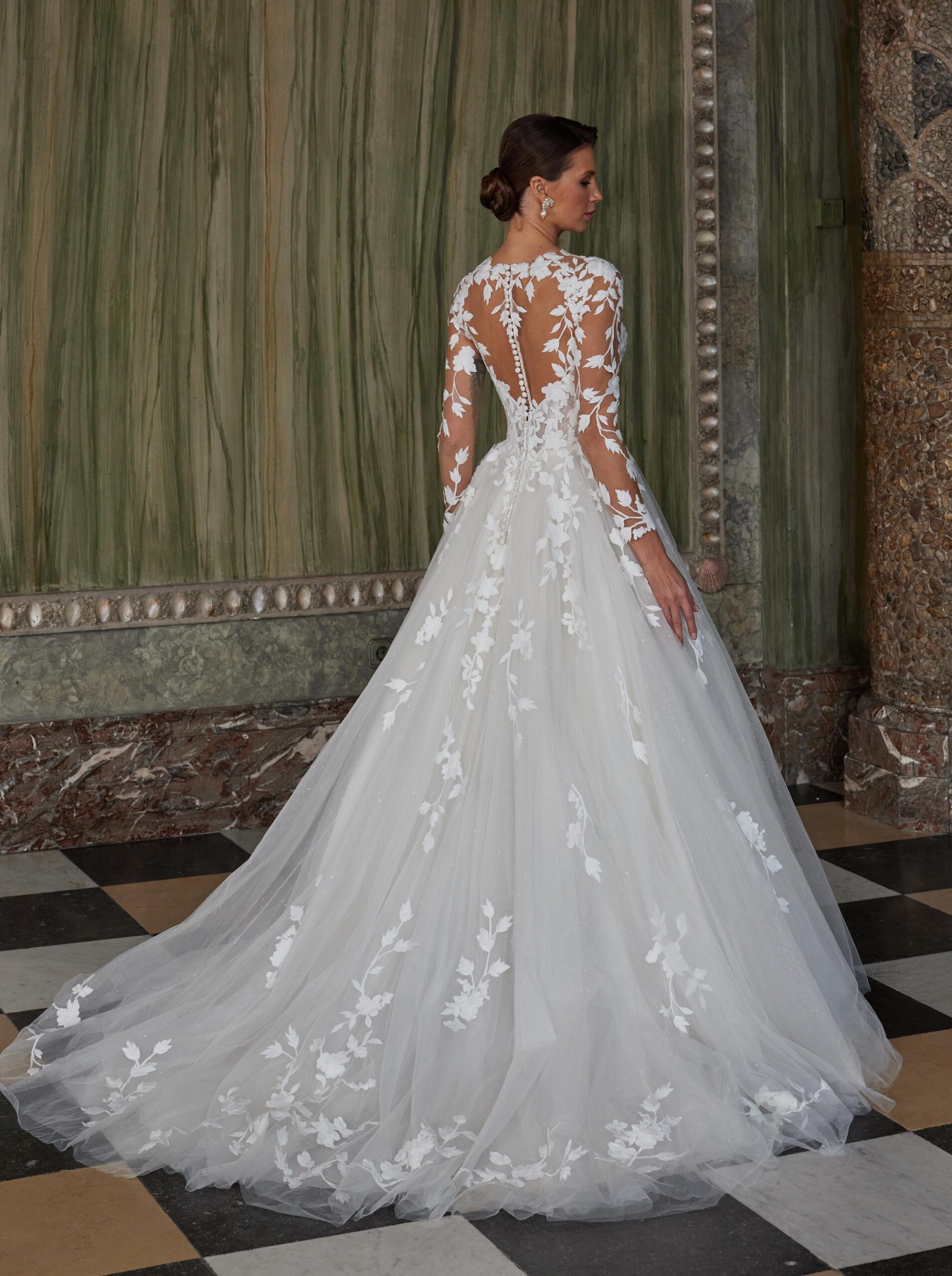 Brudklänning med 3D-blommor, spetsdetaljer, illusionrygg och skimrande tyllkjol – DE LUXE by Diane Legrand hos Jolie Bridal i Malmö.