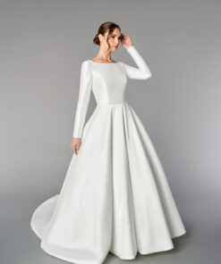 Mikadoklänning i A-linje med Sabrina-urringning, långa ärmar med knappar, prinsessömmar, V-rygg, fickor och kapellsläp med knappar hela vägen bak.