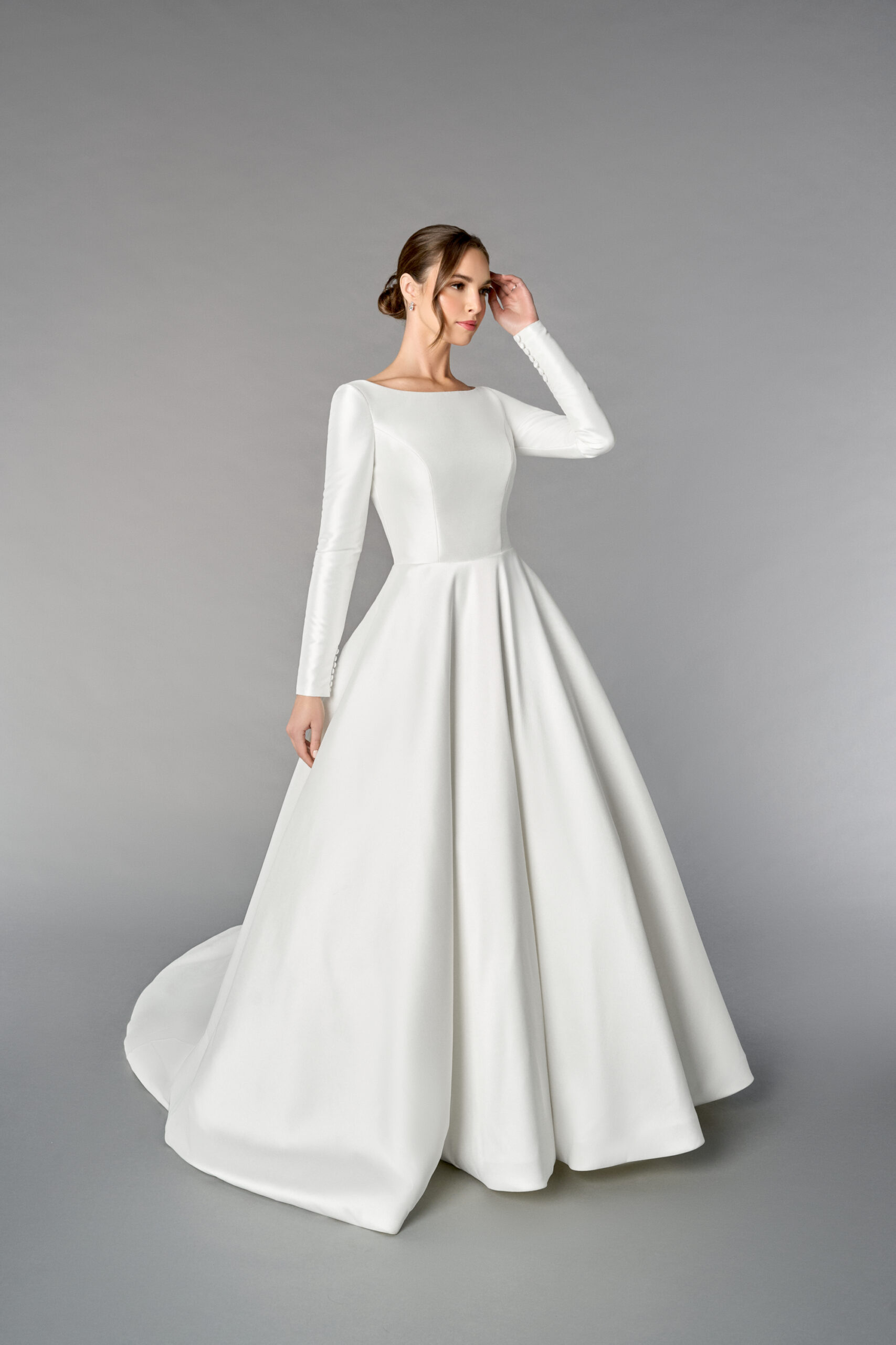 Mikadoklänning i A-linje med Sabrina-urringning, långa ärmar med knappar, prinsessömmar, V-rygg, fickor och kapellsläp med knappar hela vägen bak.