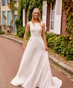 Brudklänning i mikado med A-linjeform, Sabrina-urringning, V-formad rygg och ivorfärgade applikationer med paljetter, samt kjol med fickor och svepsläp.