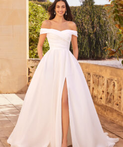 Denna drömlika A-linjeformade brudklänning i lätt och luftig organza kombinerar klassisk skönhet med moderna inslag. Det plisserade livstycket formar överkroppen vackert och ramas in av av axeln-band som ger en romantisk och tidlös känsla. Den vida kjolen har boxveck för volym och struktur, samt en diskret slits som tillför både rörelsefrihet och en touch av dramatik. Klänningen är även praktiskt designad med dolda fickor – perfekt för små personliga tillhörigheter. Baksidan pryds av organza-klädda knappar längs bodice och avslutas med ett mjukt, chapel-långt släp för en elegant finish.