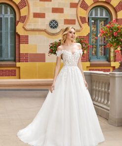 En klänning som verkligen för tankarna till stjärnklara nätter – denna off-the-shoulder ball gown är både drömsk och sofistikerad. Under kjolens lager döljer sig en skimrande galaxy-tyll, som ger ett subtilt stjärnglitter vid varje steg. Det transparenta livstycket har synlig boning för struktur, och är rikt dekorerat med paljettspetsapplikationer, överlagrade med handplacerade 3D-spetsblommor som mjukt flyter ned över kjolen och skapar ett förtrollande djup. Klänningens rygg är modest med en mjuk form, och avslutas med galaxy-tyllklädda knappar som ger en elegant och genomtänkt finish. Det hela rundas av med ett mjukt, svepande släp, perfekt för en sagoinspirerad entré.