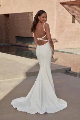 Romantisk brudklänning i crepe med fit and flare-siluett, låg nyckelhålsrygg och illusionband från Jolie Bridal i Malmö.