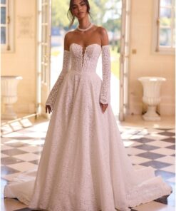 Modern brudklänning i big ball gown-modell i guipure-spets med lång släp, trumpetärmar och pärlbroderad basque-midja.